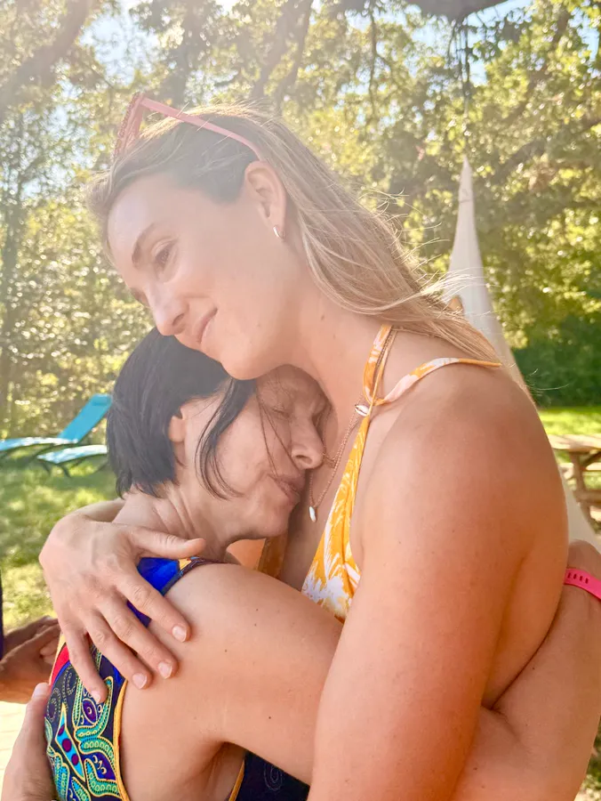 Two women embracing by the pond