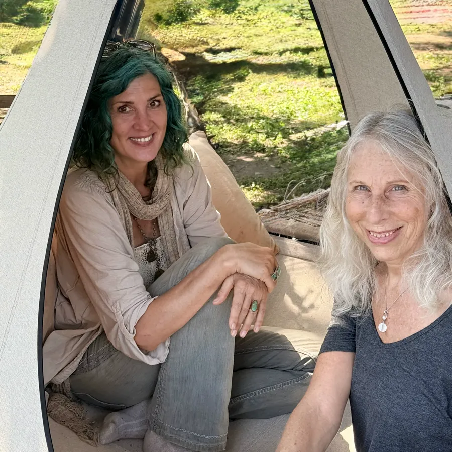 Two women smiling inside a hanging tent
