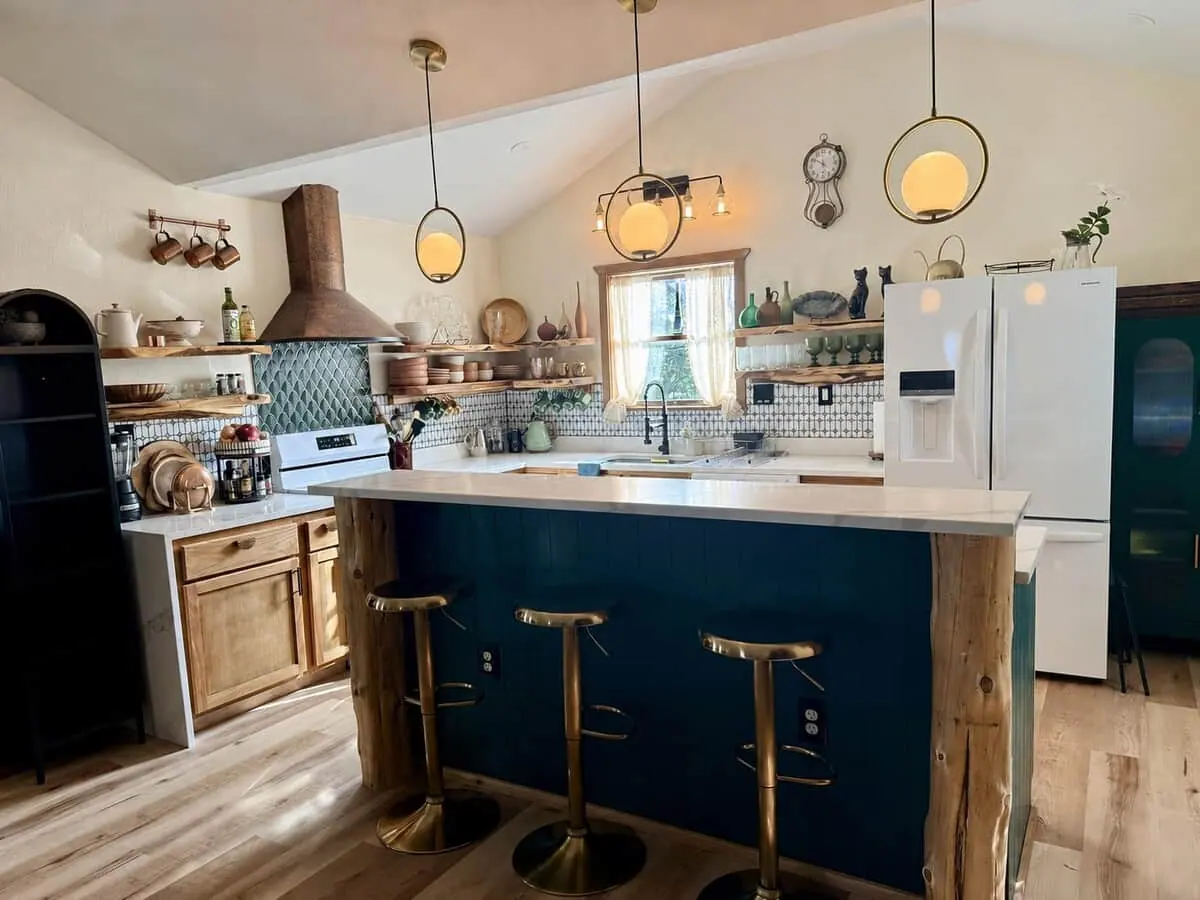 The kitchen with a teal island and brass stools