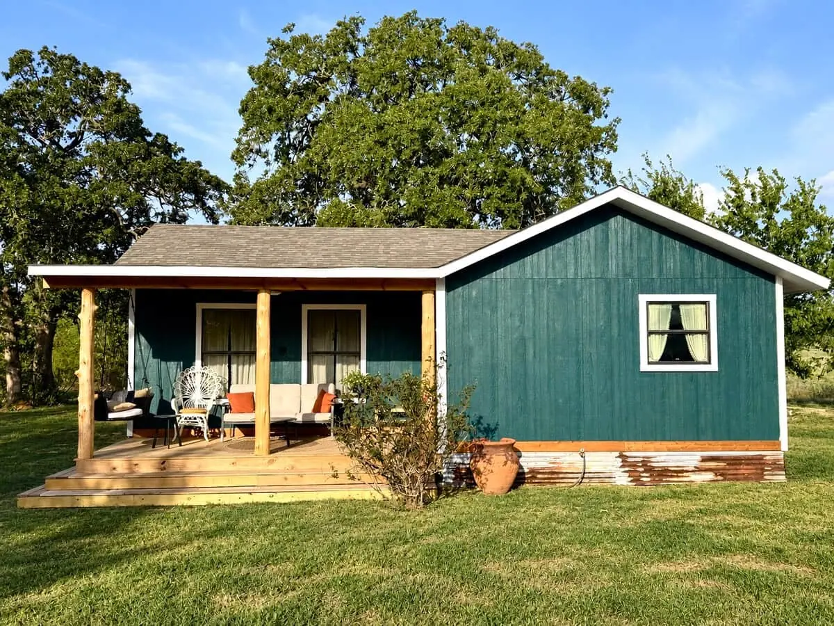The Care Cottage from outside: a teal house with a front porch