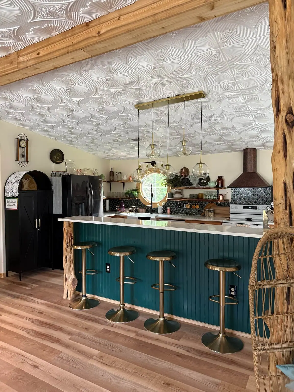 The teal and gold kitchen island with brass pendants