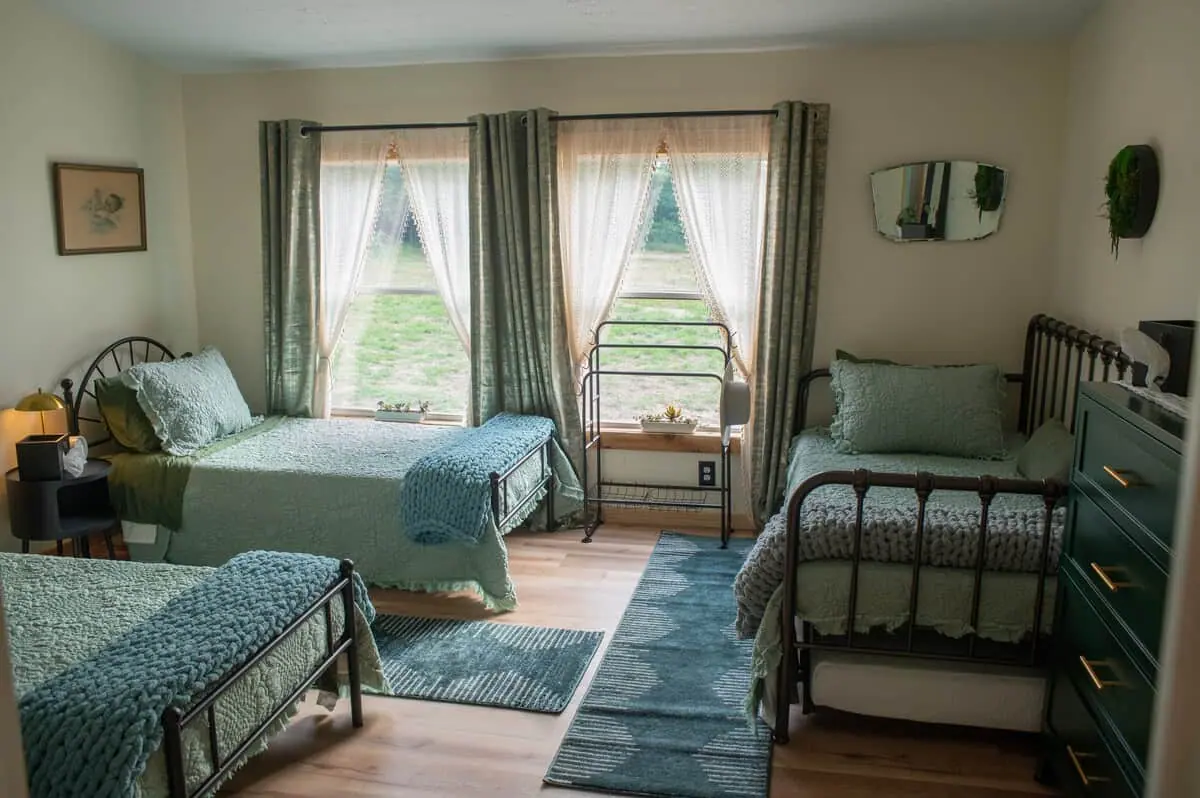 A sage-green bedroom with three beds